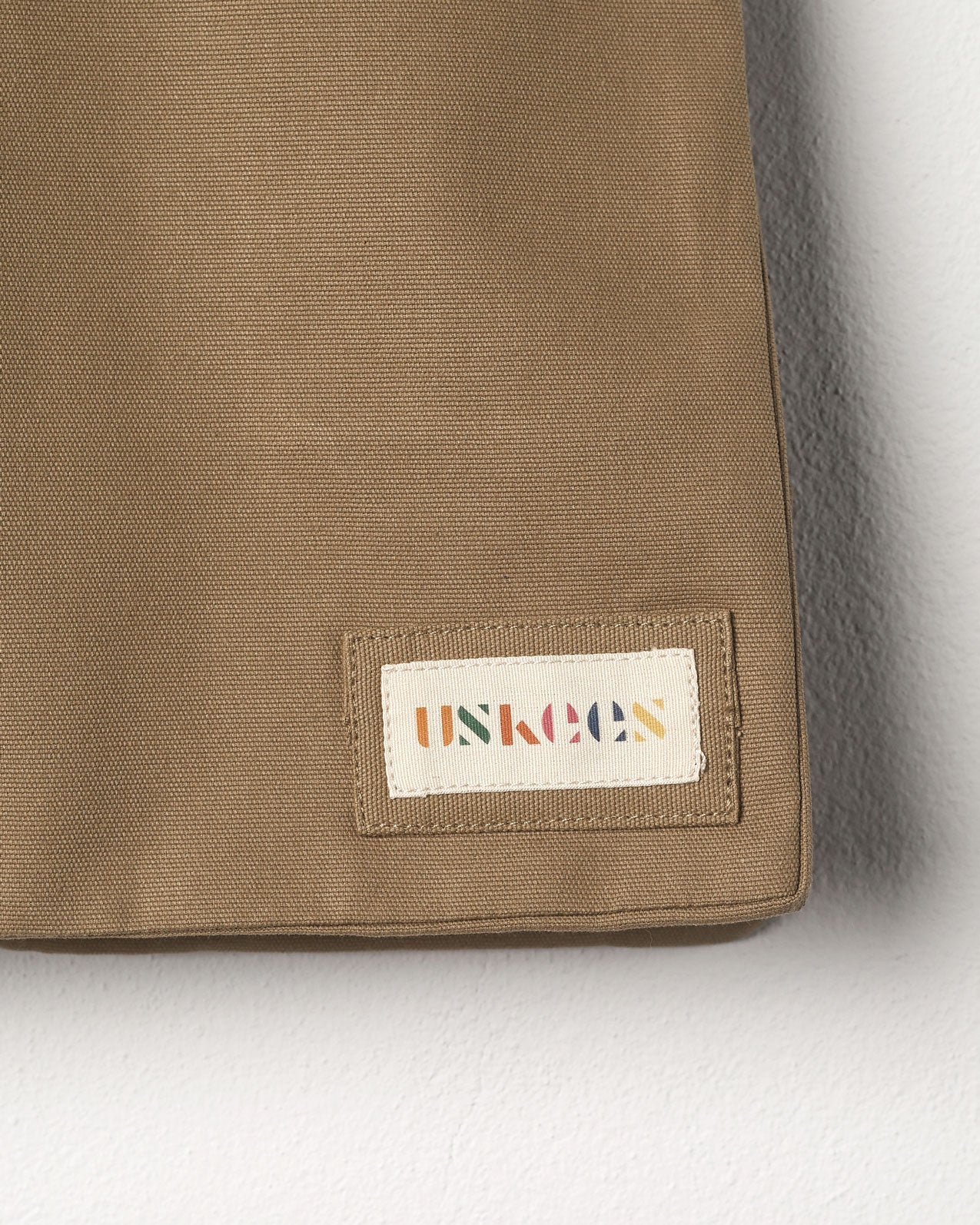 Close-up view of Uskees #4002 small tote bag in khaki showing the Uskees woven label.
