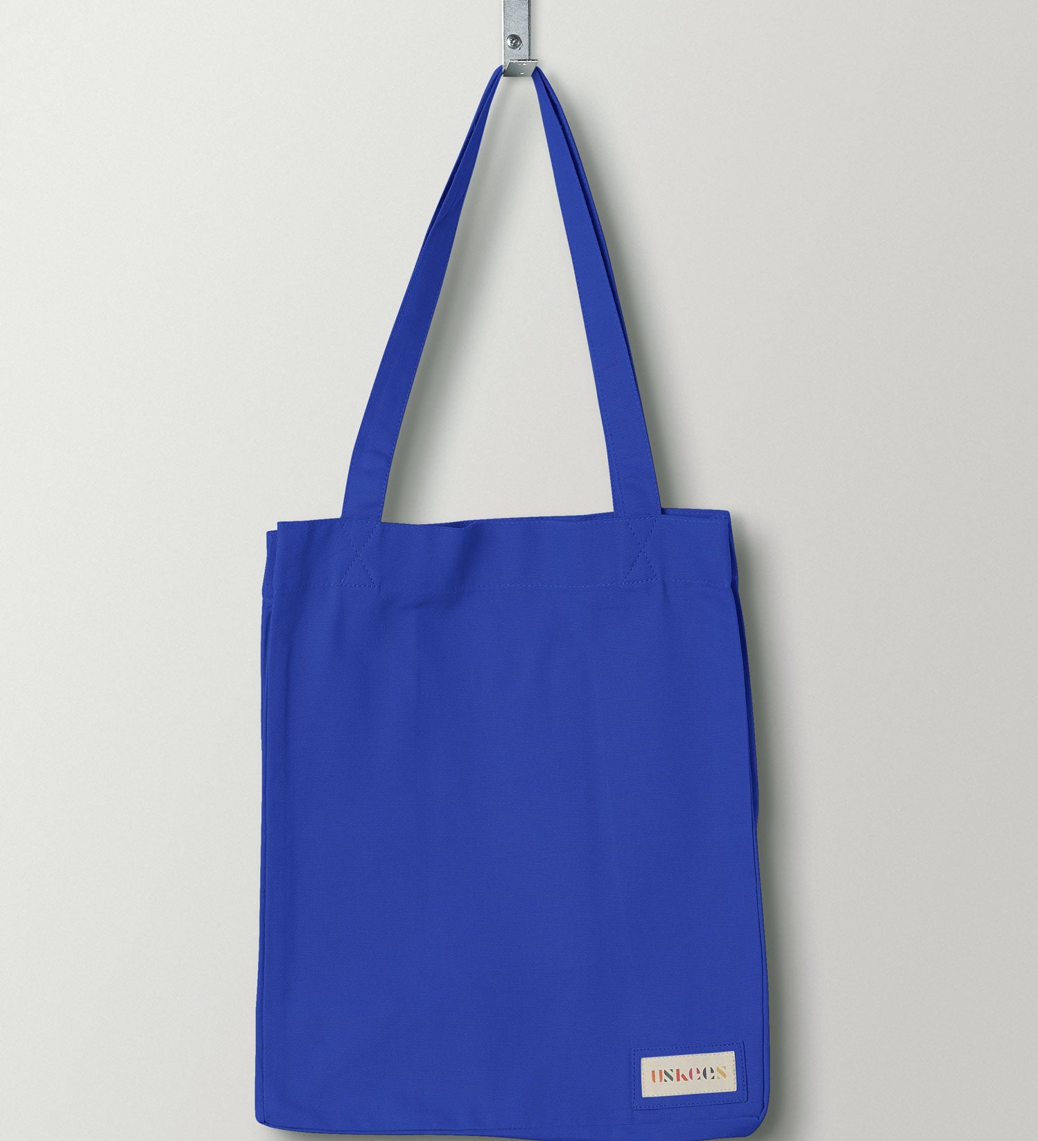 Full front hanging shot of Uskees #4002 small ultra-blue tote bag, showing double handles and Uskees woven logo.