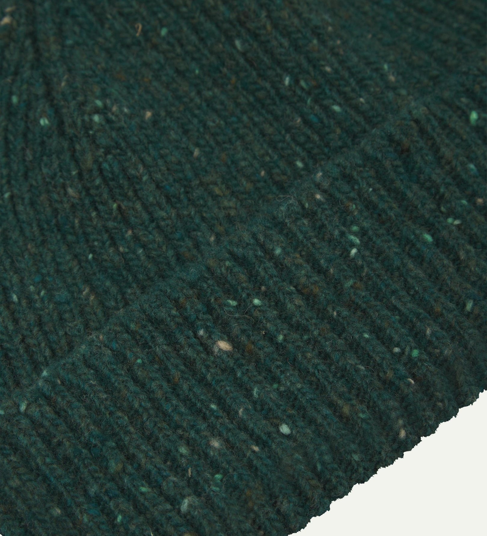 Close-up of the 'mallard green' donegal wool hat from Uskees, clearly showing the ribbing and multicoloured 'speckled' detail and texture of the natural Scottish merino wool.