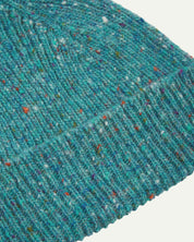 Close-up of the 'ocean green' donegal wool hat from Uskeed, clearly showing the ribbing and multicoloured 'speckled' detail and texture of the natural Scottish merino wool.