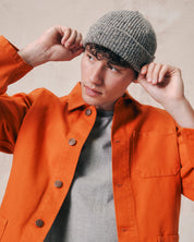 Male model wearing Uskees 4003 'silver-grey' speckled donegal wool hat. Paired with gold Uskees shirt.