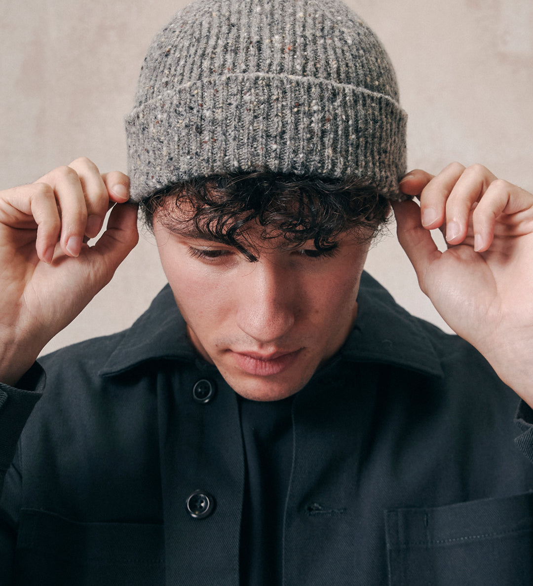 Male model wearing the Uskees 4003 'silver-grey' speckled donegal wool hat. Paired with faded black Uskees shirt.