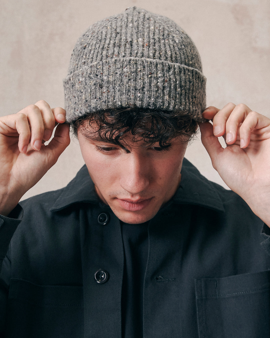 Male model wearing the Uskees 4003 'silver-grey' speckled donegal wool hat. Paired with faded black Uskees shirt.