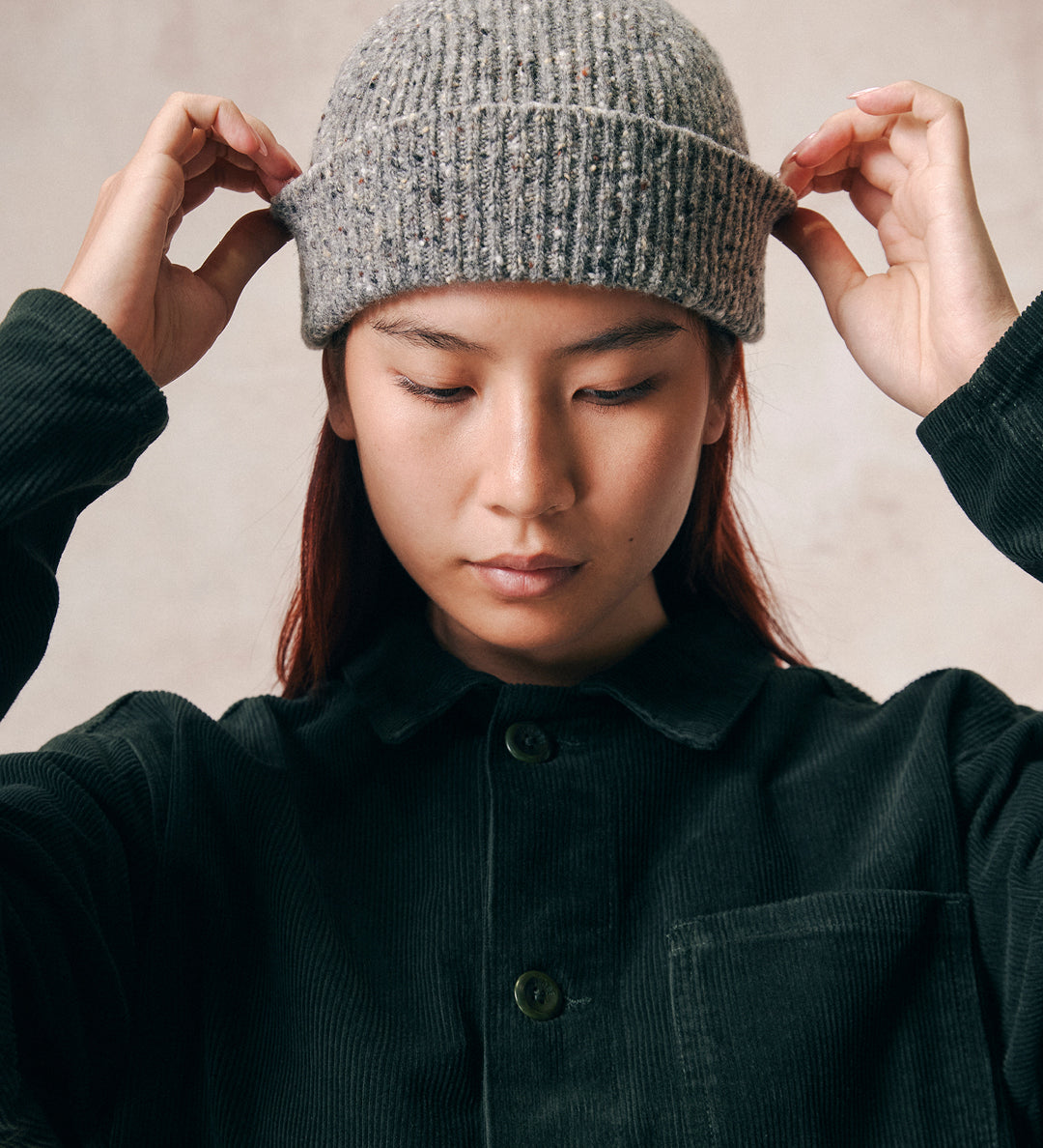 Female model wearing Uskees 4003 'silver-grey' speckled donegal wool hat. Paired with dark green corduroy Uskees shirt.