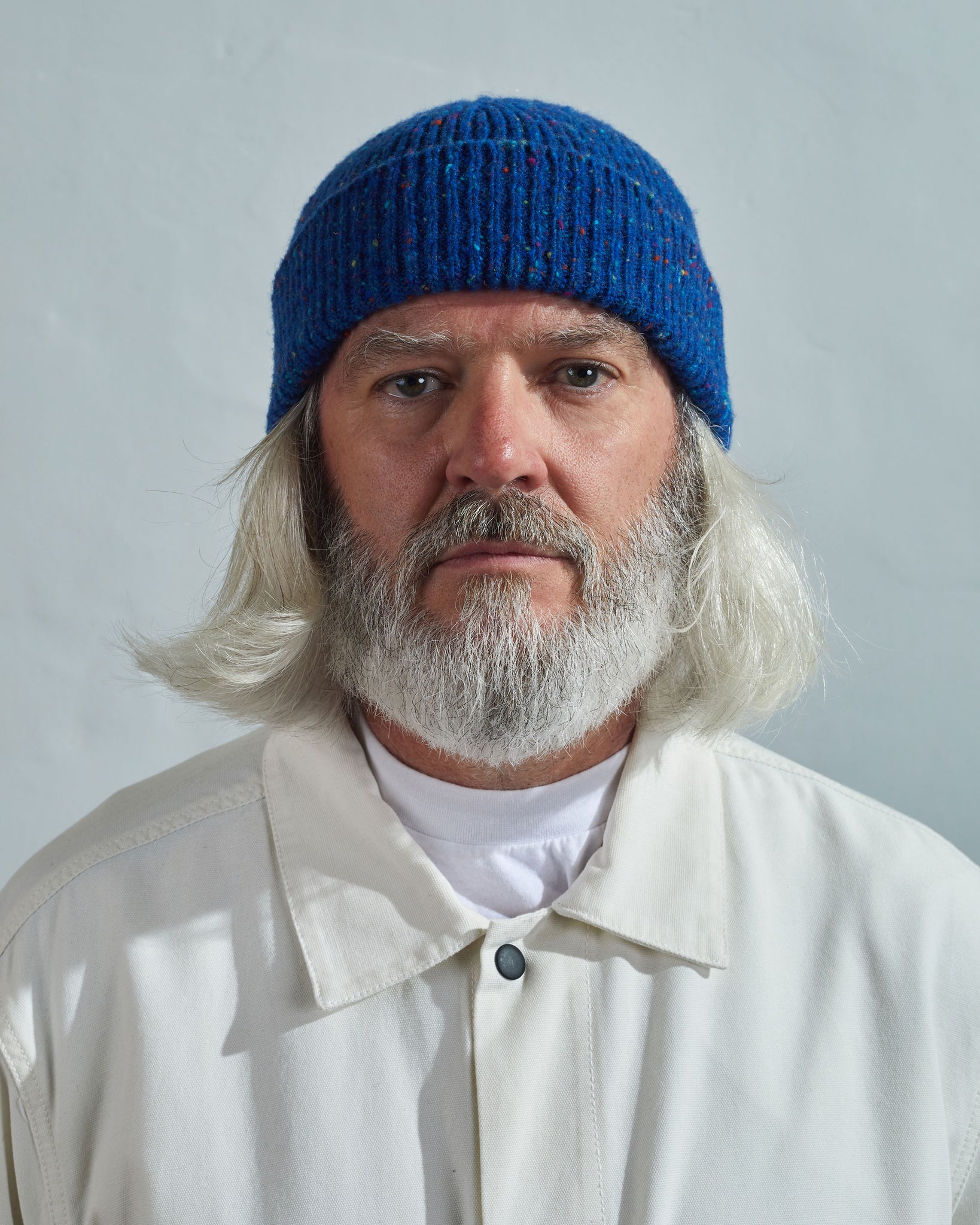 Model wearing Uskees 4003 'ultra blue' Donegal wool hat, paired with white Uskees jacket.