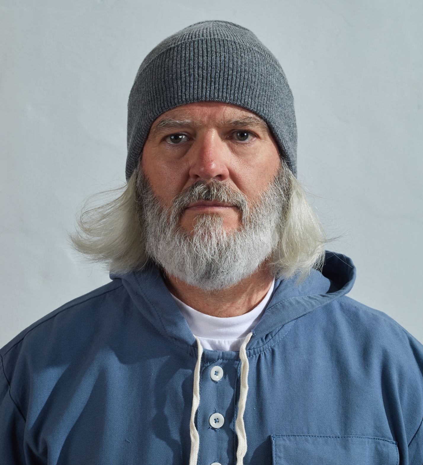 Man wearing Uskees 4004 grey lambswool hat, paired with blue Uskees smock.