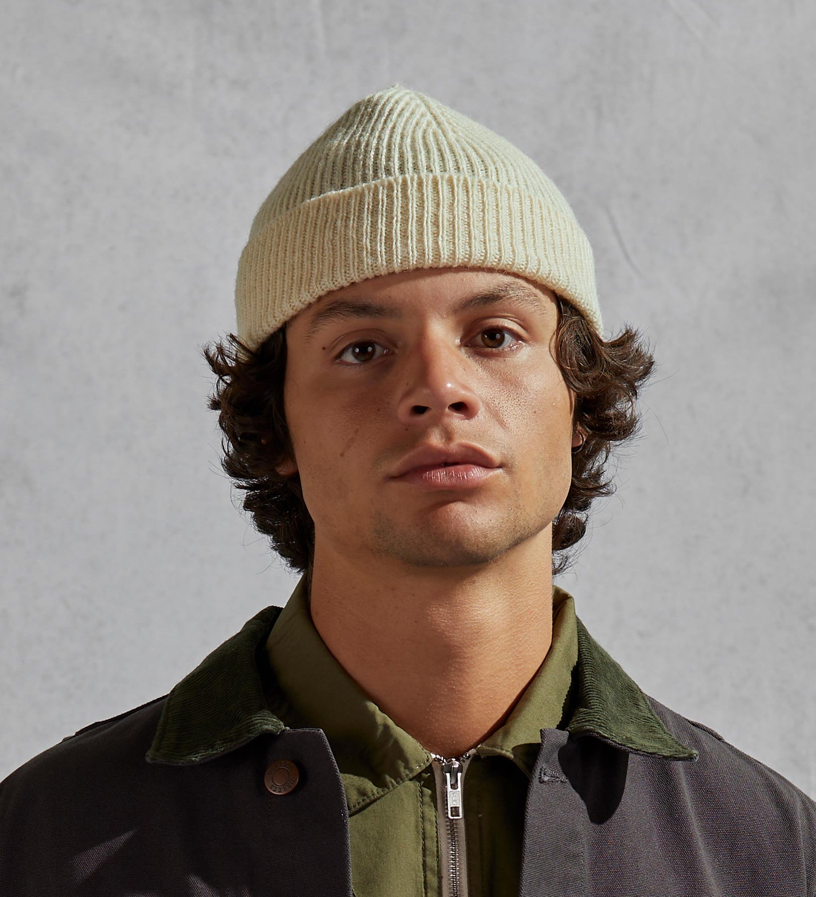 Man wearing Uskees 4005 'light oat' grey coloured wool hat, paired with green Uskees jacket.