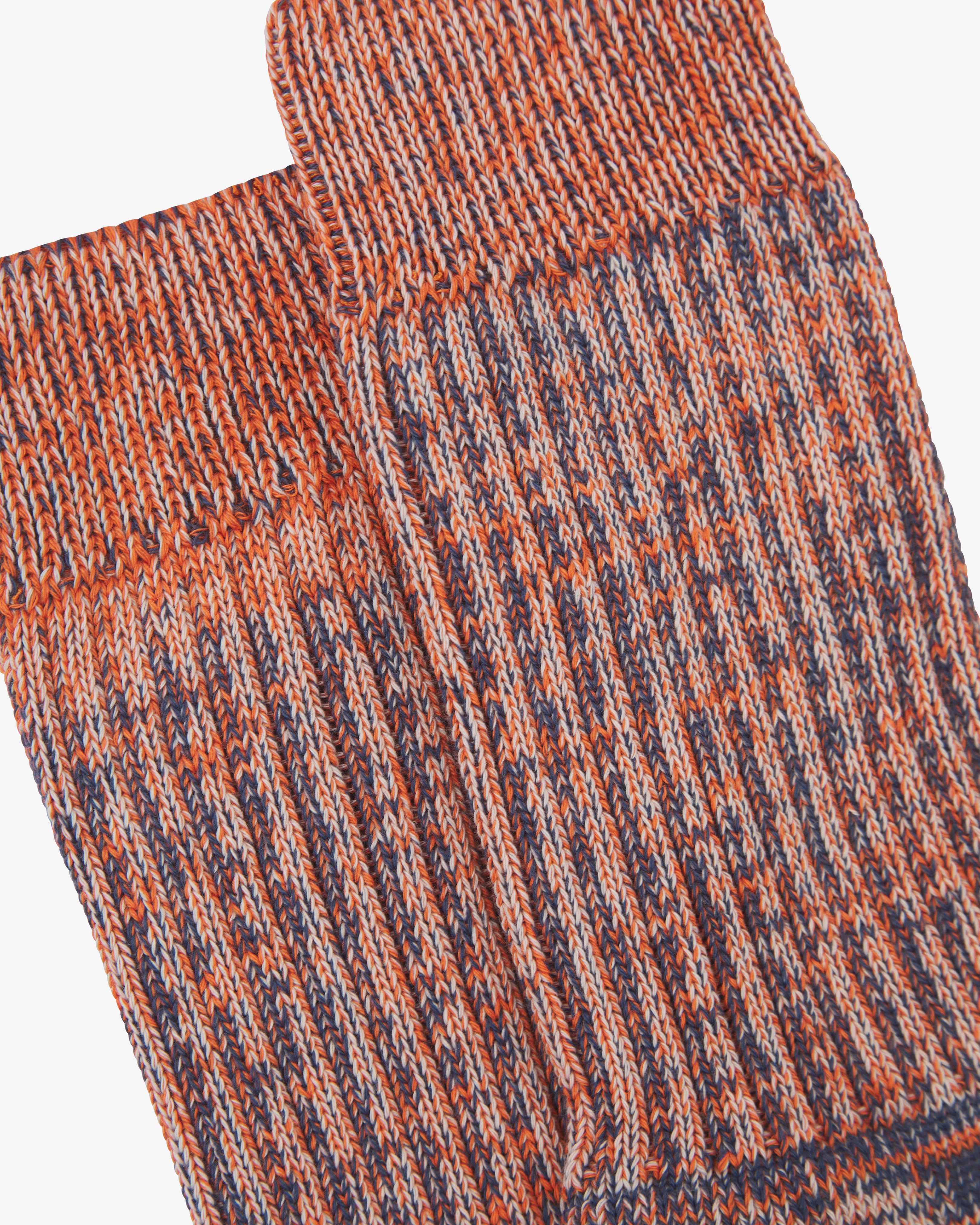Close-up of pair of Uskees Men's socks in orange stripe pattern showing rib detail.