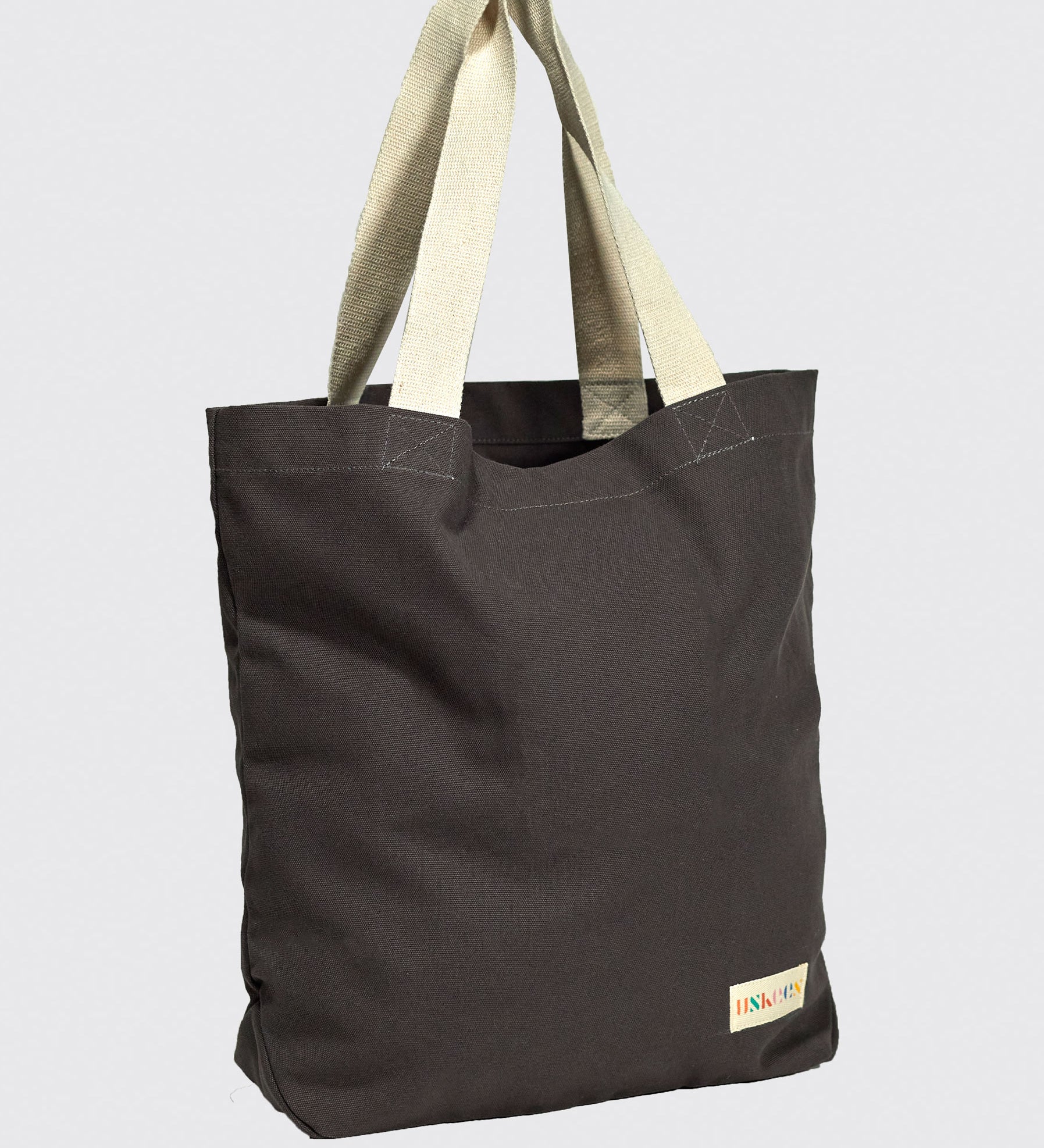 Slightly angled front view of Uskees #4009 'charcoal' coloured canvas tote bag, showing double webbing straps and Uskees woven logo.