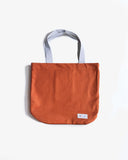 Uskees orange canvas tote bag with cream handles showing the brand label, on a white background