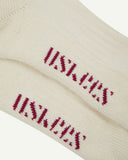 Pair of Uskees men's white sport socks showing the 'USKEES' branding on the sole on a white background