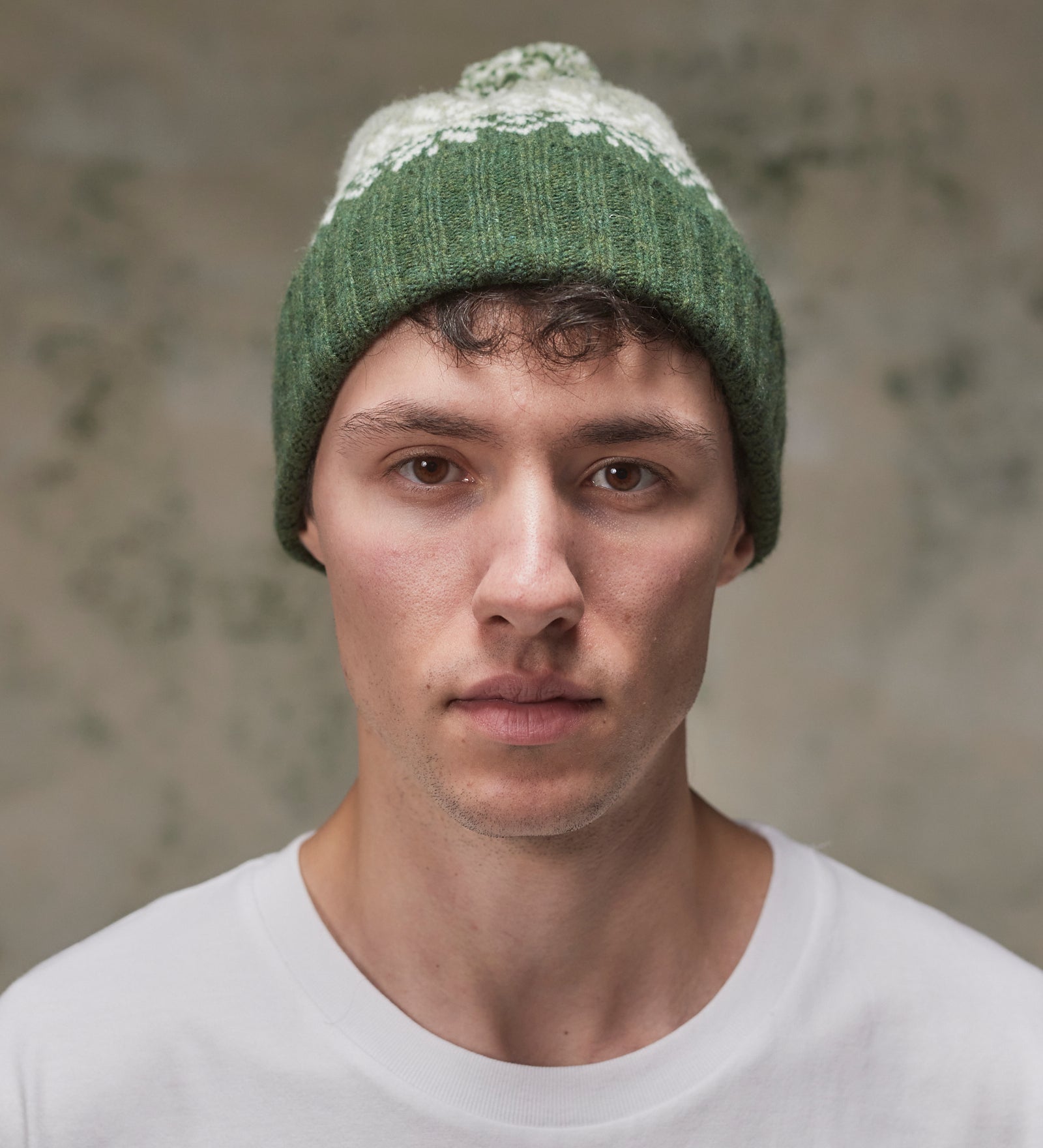 Front view of model wearing the coriander Fair Isle pattern hat from Uskees, clearly showing the ribbing of the adjustable cuff.