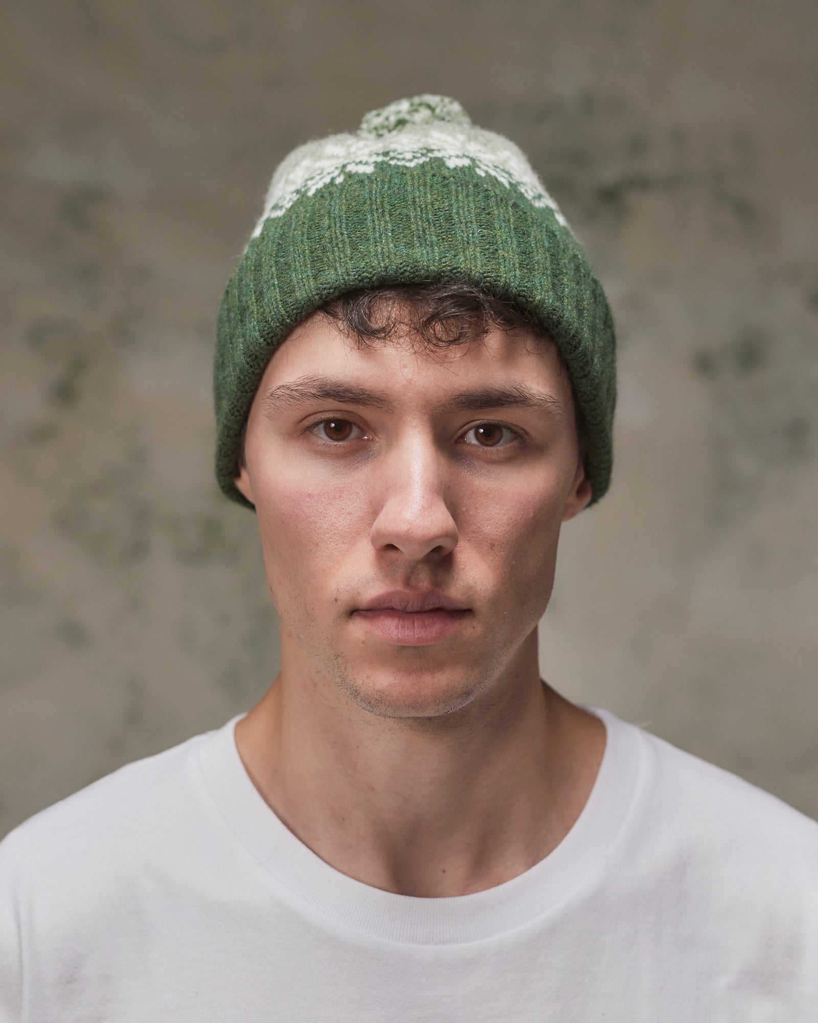 Front view of model wearing the coriander Fair Isle pattern hat from Uskees, clearly showing the ribbing of the adjustable cuff.