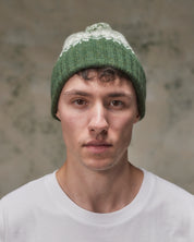 Front view of model wearing the coriander Fair Isle pattern hat from Uskees, clearly showing the ribbing of the adjustable cuff.