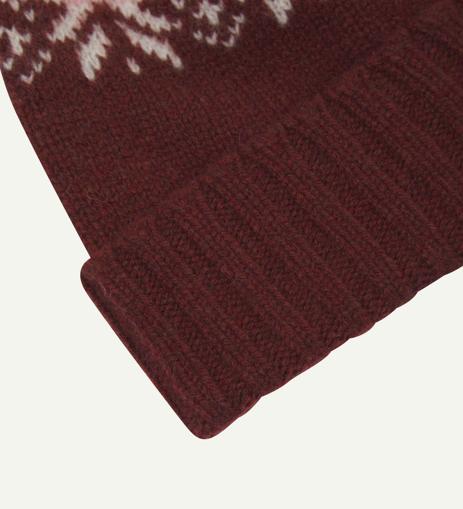 Close-up of the dusty pink snowflake hat from Uskees, clearly showing the ribbing of the adjustable cuff and texture of the natural Scottish lambswool.