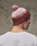Back view of model wearing the dusty pink Fair Isle pattern hat from Uskees, clearly showing the tricolour design, snowflakes and bobble.