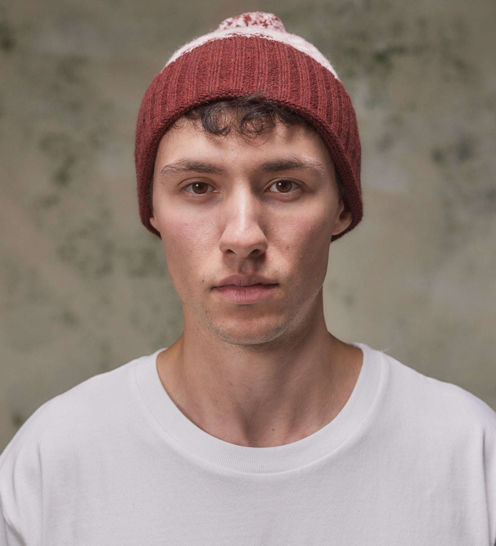 Front view of model wearing the dusty pink Fair Isle pattern hat from Uskees, clearly showing the ribbing of the adjustable cuff.