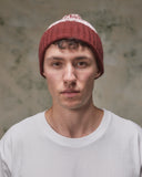 Front view of model wearing the dusty pink Fair Isle pattern hat from Uskees, clearly showing the ribbing of the adjustable cuff.