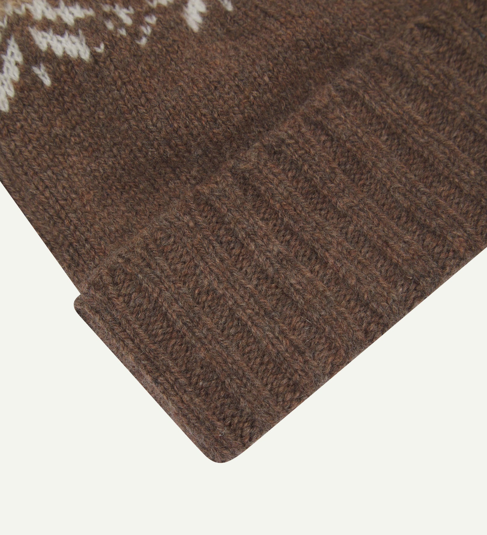 Close-up of the khaki snowflake hat from Uskees, clearly showing the ribbing of the adjustable cuff and texture of the natural Scottish lambswool.