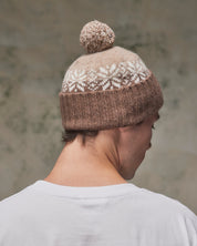 Back view of model wearing the khaki Fair Isle pattern hat from Uskees, clearly showing the tricolour design, snowflakes and bobble.