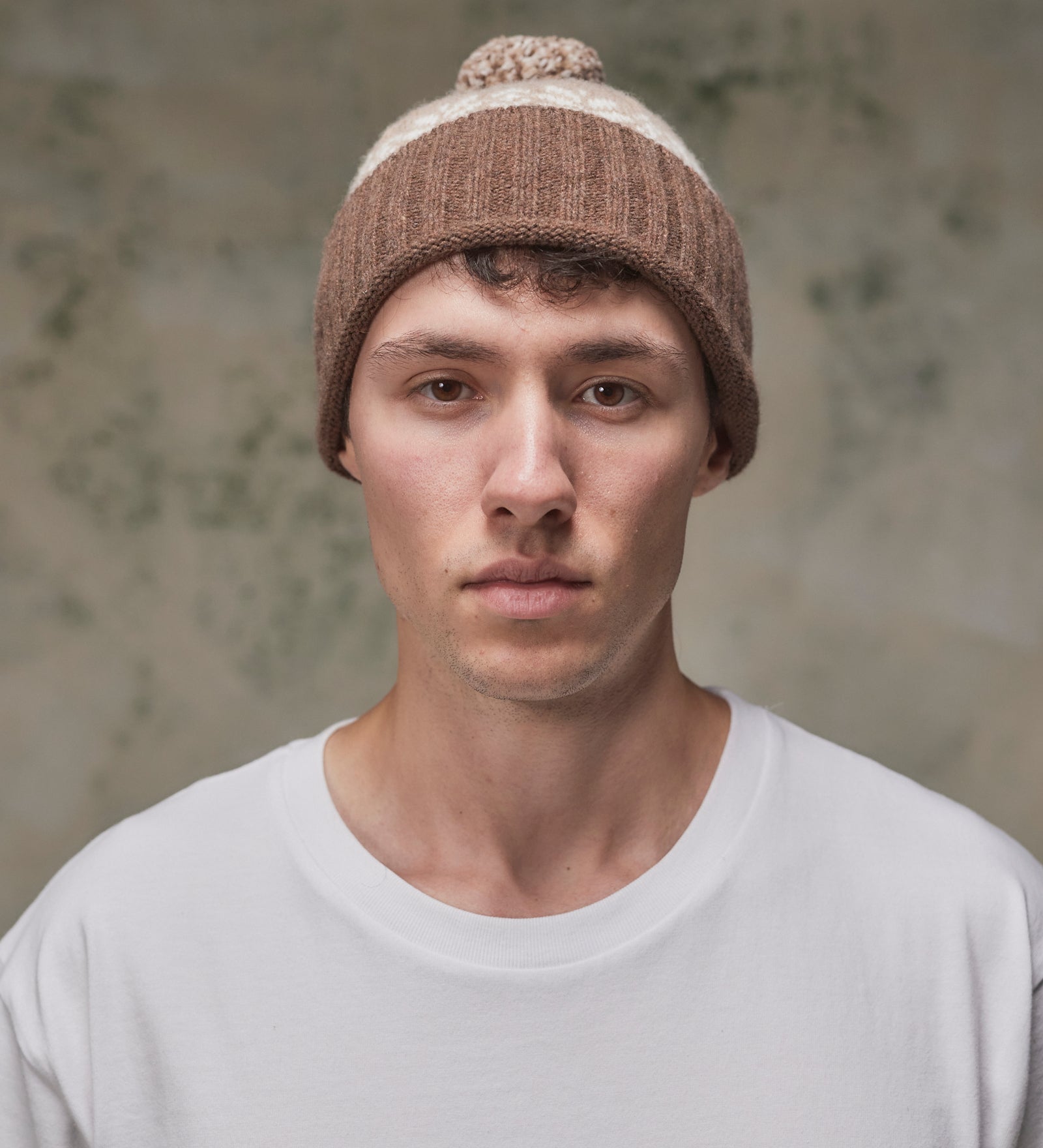 Front view of model wearing the khaki Fair Isle pattern hat from Uskees, clearly showing the ribbing of the adjustable cuff.