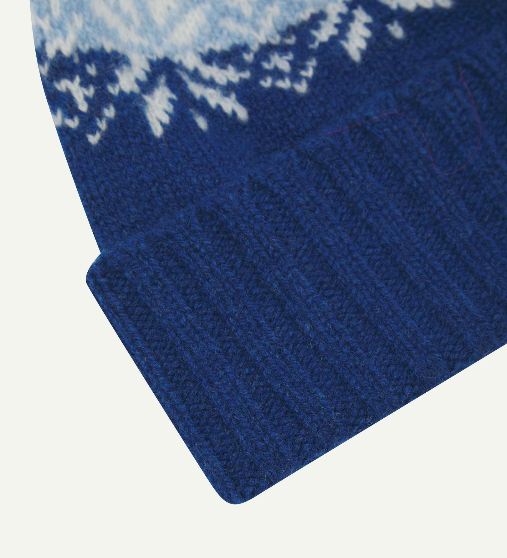 Close-up of the ultra blue snowflake hat from Uskees, clearly showing the ribbing of the adjustable cuff and texture of the natural Scottish lambswool.