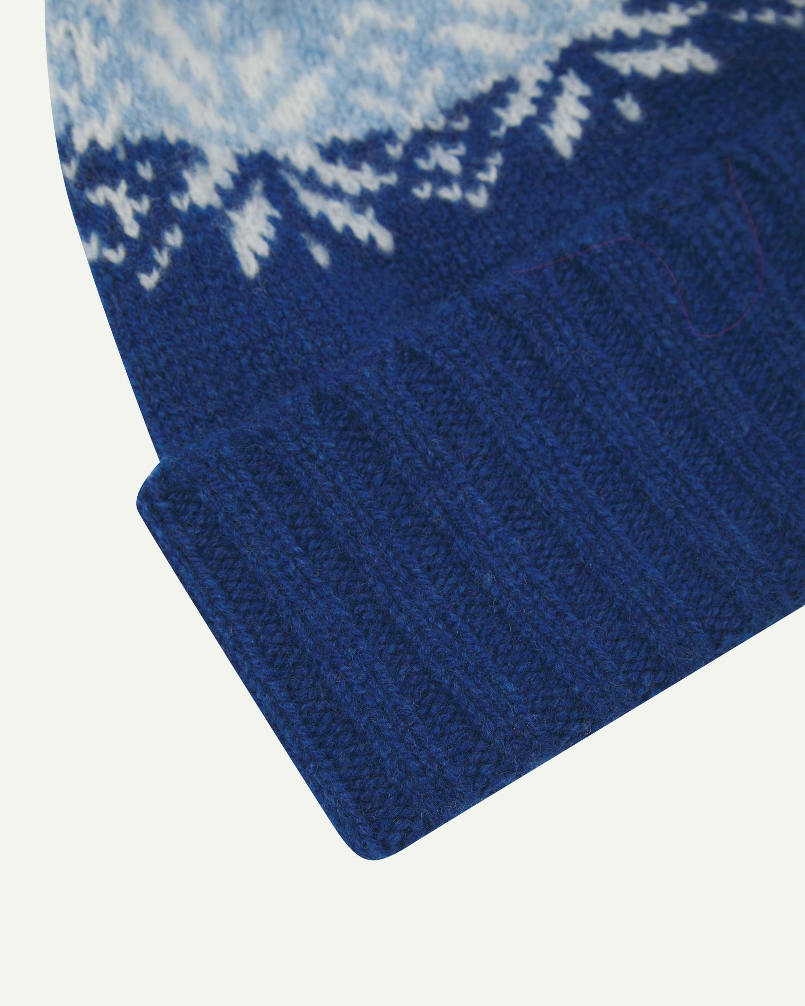 Close-up of the ultra blue snowflake hat from Uskees, clearly showing the ribbing of the adjustable cuff and texture of the natural Scottish lambswool.