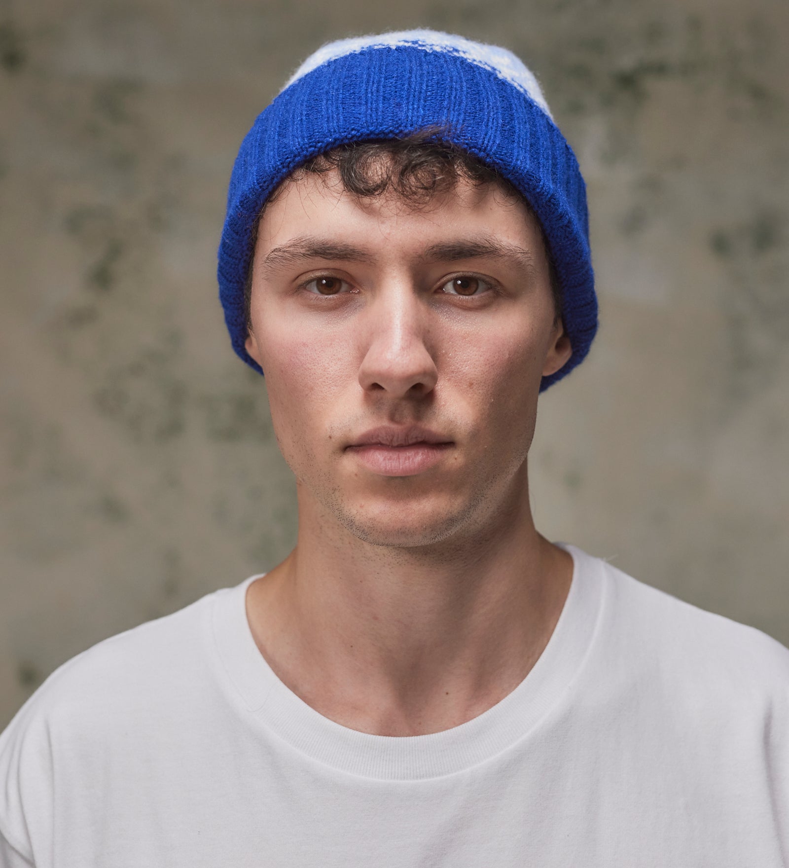 Front view of model wearing the ultra blue Fair Isle pattern hat from Uskees, clearly showing the ribbing of the adjustable cuff.