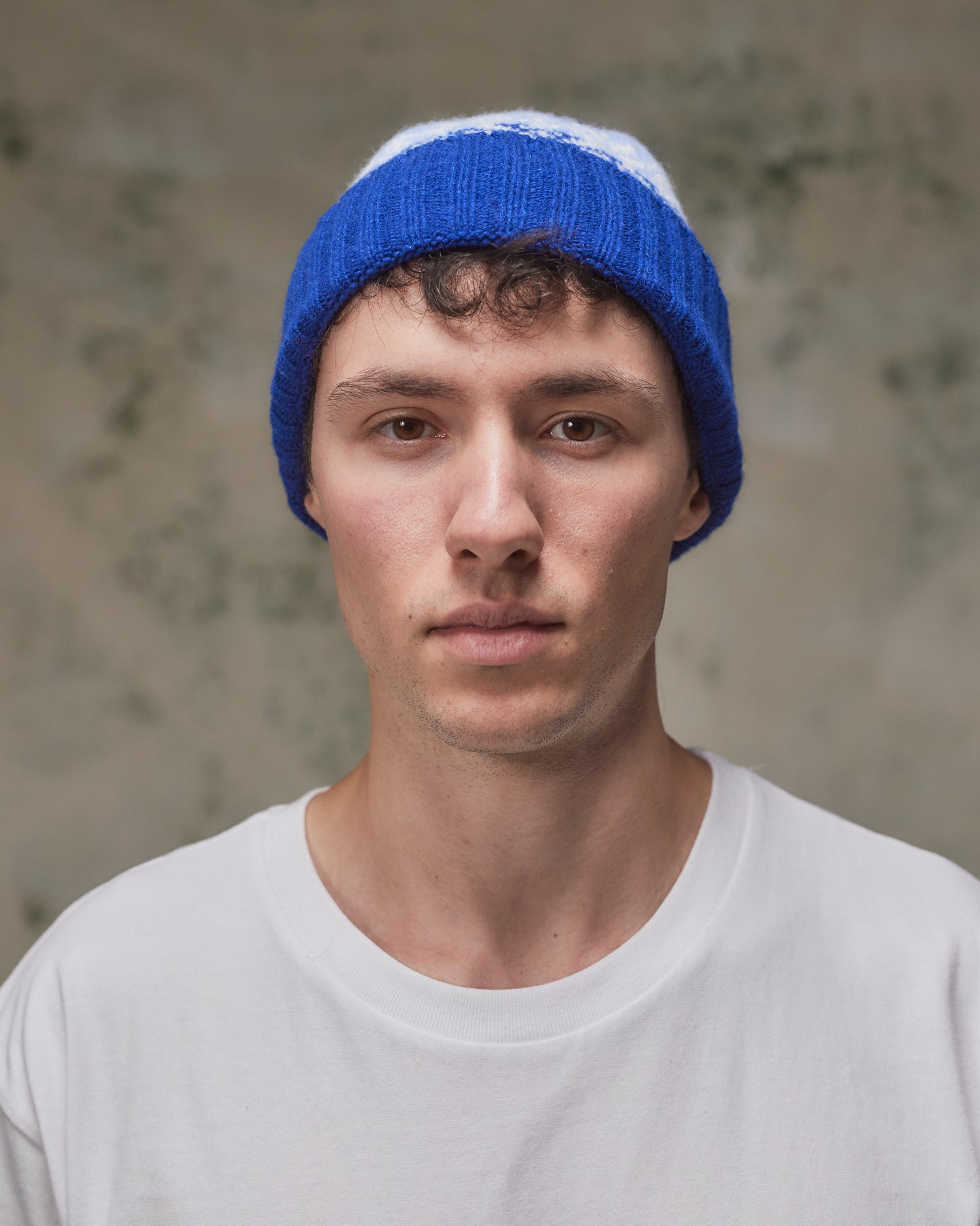 Front view of model wearing the ultra blue Fair Isle pattern hat from Uskees, clearly showing the ribbing of the adjustable cuff.