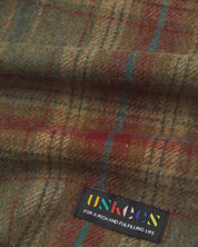 Close up view of Uskees tartan lambswool scarf showing the green and red pattern and uskees brand label.