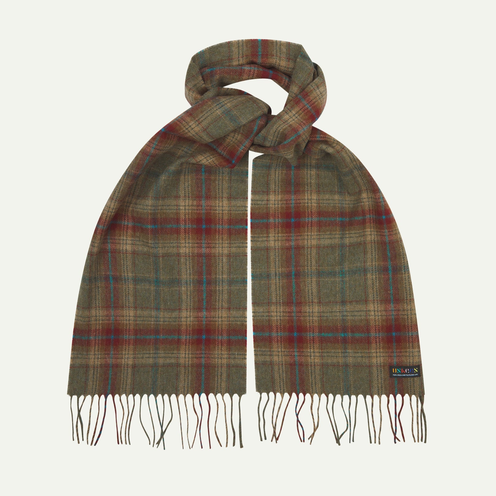 Uskees scarf presented on a flat white surface - tied and showing the green and red check pattern and tassels.