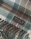 Close up view of Uskees tartan lambswool scarf showing the green, brown and gold check pattern pattern and Uskees brand label.