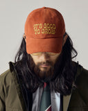 Model wearing Chestnut brown Uskees 6-panel cap with 'It's Good to Grow' embroidered motif in gold.