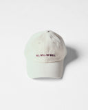 Cream Uskees 6-panel cap with 'All Will Be Well' embroidered motif in maroon.