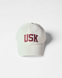 Cream Uskees 6-panel cap with 'USK' embroidered motif in maroon.