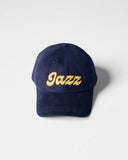 Navy blue Uskees 6-panel cap with 'Jazz' embroidered motif in gold.