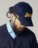 Model wearing navy blue Uskees 6-panel cap with 'Jazz' embroidered motif in gold.