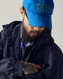Model wearing bright blue Uskees 6-panel cap with 'It's Good to Grow' embroidered motif in green.