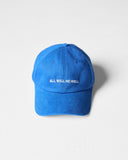 Bright blue Uskees 6-panel cap with 'All Will Be Well' embroidered motif in cream.