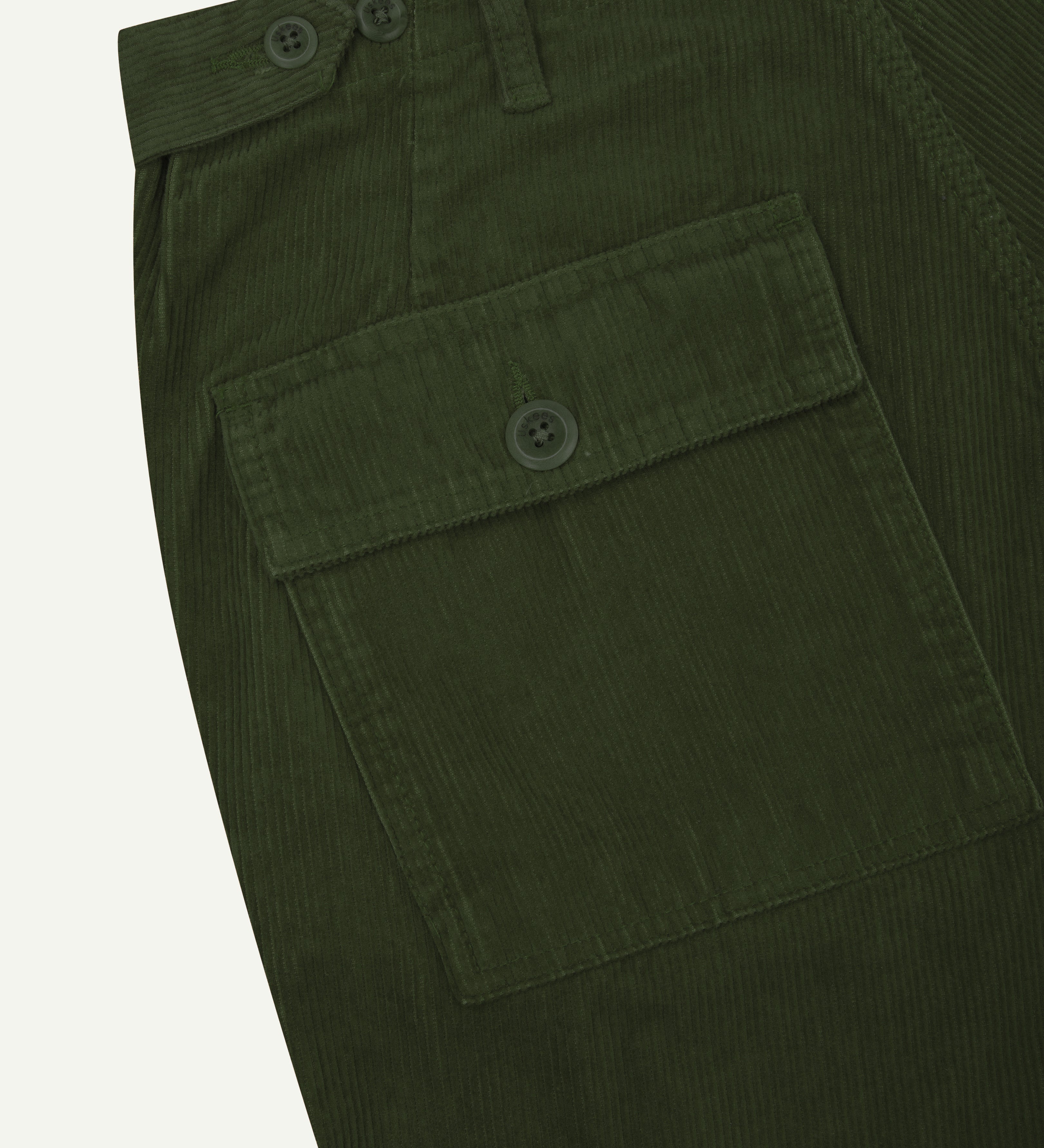 Close up shot of Uskees coriander green #5005 cord workwear pants showing pocket and waist detail.
