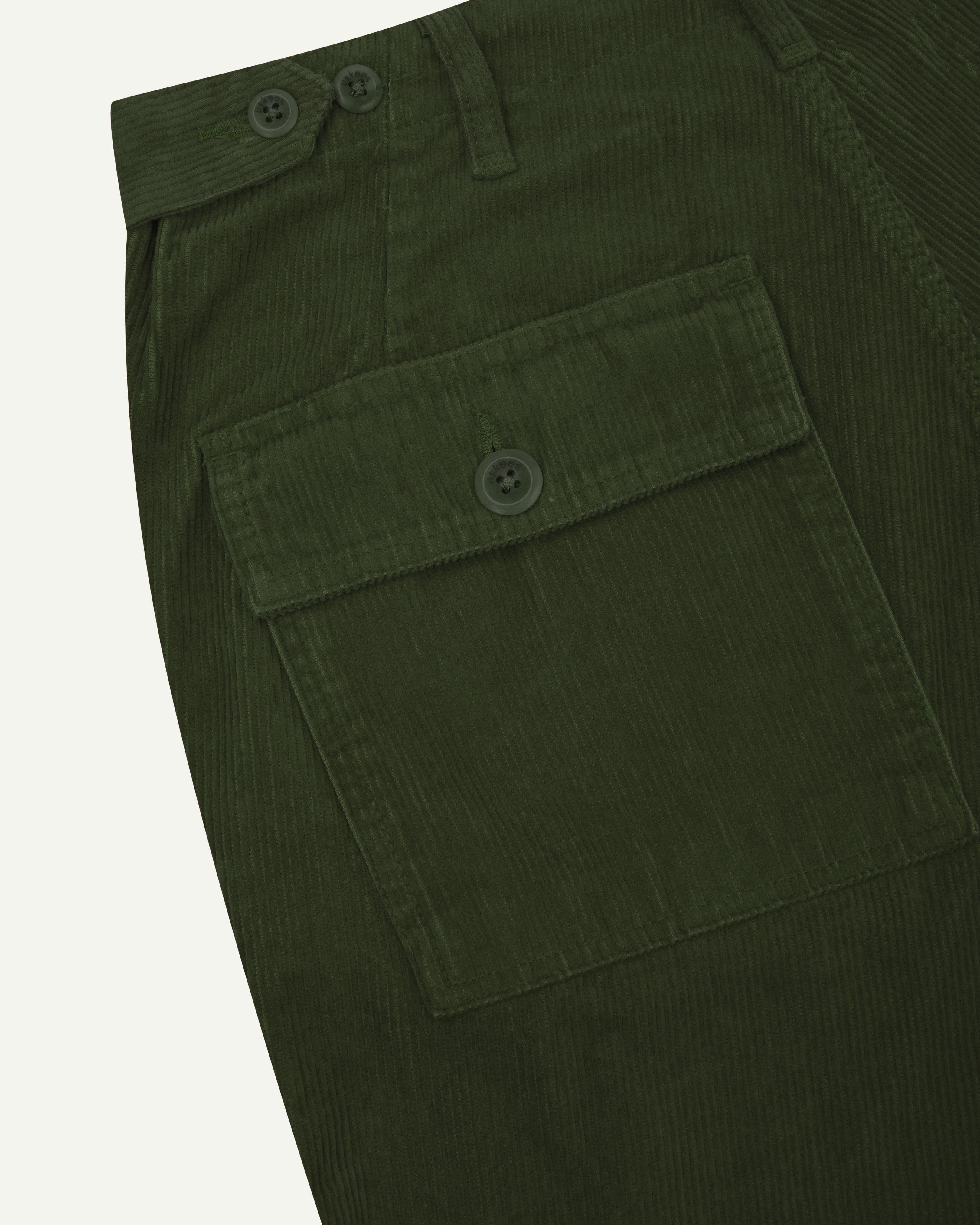 Close up shot of Uskees coriander green #5005 cord workwear pants showing pocket and waist detail.