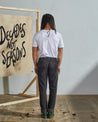 Full length back-view of model wearing faded black corduroy 5005 trousers with view of rear pockets and belt loops.