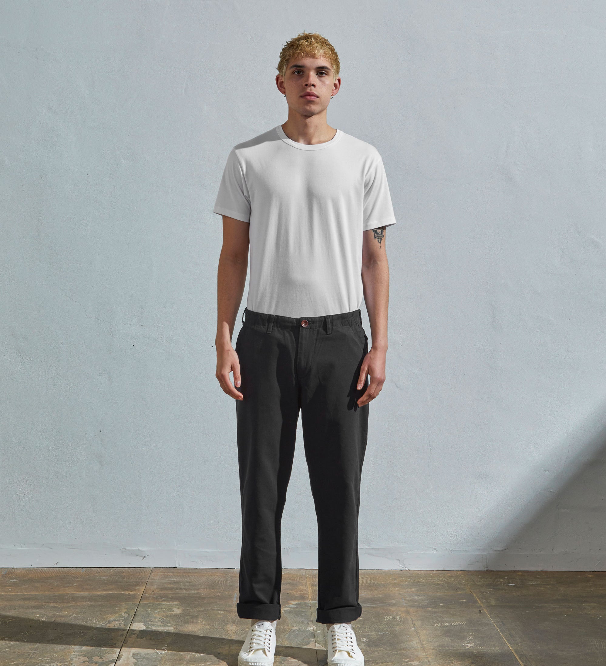 Full length front-view of model wearing discontinued black 5005 trousers with view of YKK zip fly and Corozo buttons. Paired with plain white t-shirt.