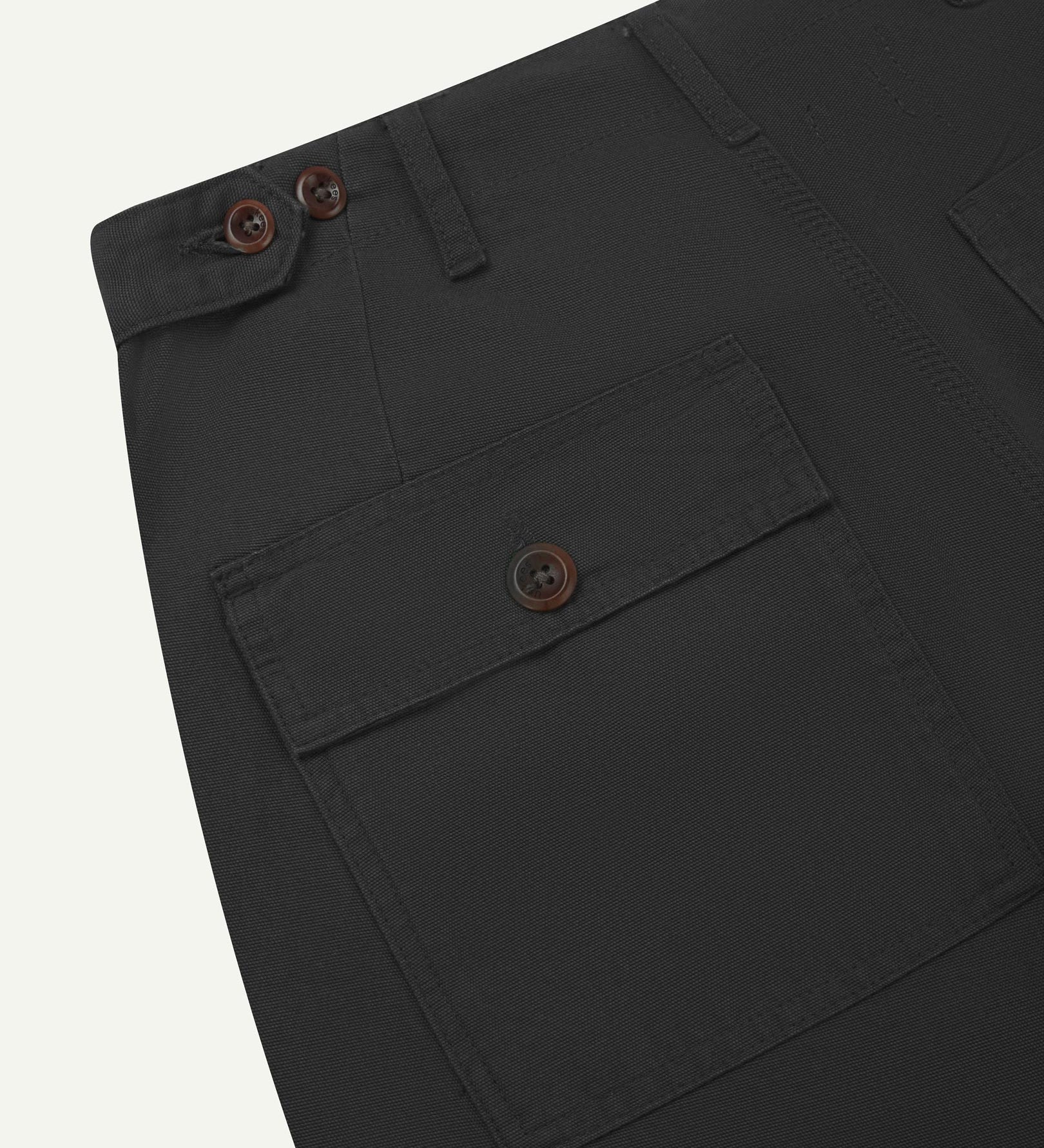 Close-up reverse view of Uskees charcoal-grey cotton work pants with focus on left rear pocket, belt loops, triple stitching and adjustable button waist.