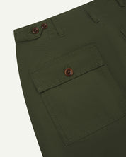 Close-up reverse view of Uskees coriander-green cotton work pants with focus on left rear pocket, belt loops, triple stitching and adjustable button waist.