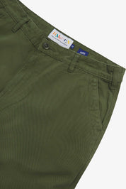 Close up of waist area of twill workwear pants in coriander-green. Clear view of front pocket, Corozo button fastening, Uskees branding label and organic cotton twill weave.