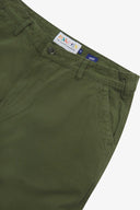 Close up of waist area of twill workwear pants in coriander-green. Clear view of front pocket, Corozo button fastening, Uskees branding label and organic cotton twill weave.