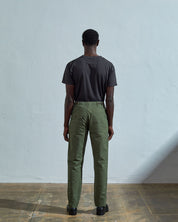 Full length back-view of model wearing bright turquoise, 'coriander-green' coloured organic cotton #5005 work trousers with view of rear and cargo pockets. 
