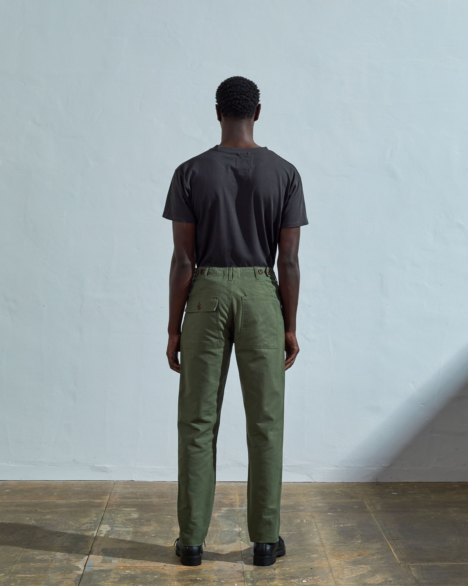 Full length back-view of model wearing bright turquoise, 'coriander-green' coloured organic cotton #5005 work trousers with view of rear and cargo pockets. 