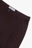 Close-up view of dark plum colour trousers showing the waistband, button closure, belt loop, and a visible USKEES brand label.